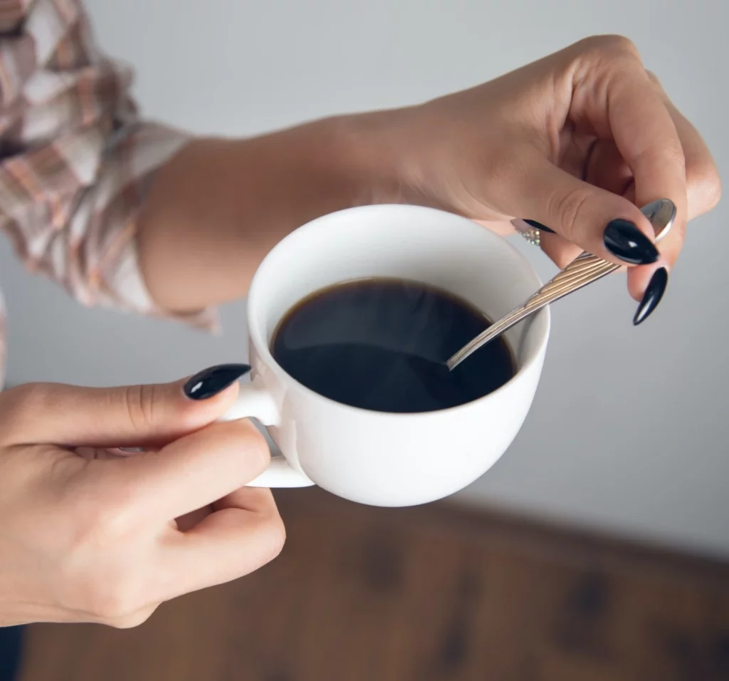 Holding a cup of black coffee