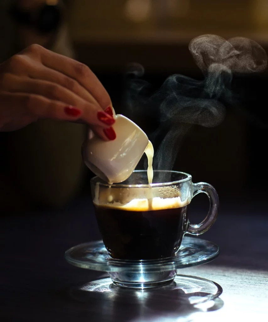 Pouring milk in black coffee